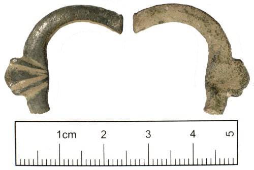 Archaeological find of a broken medieval buckle with scallop decoration, measuring 5cm, serving as a historical reference for replicas.