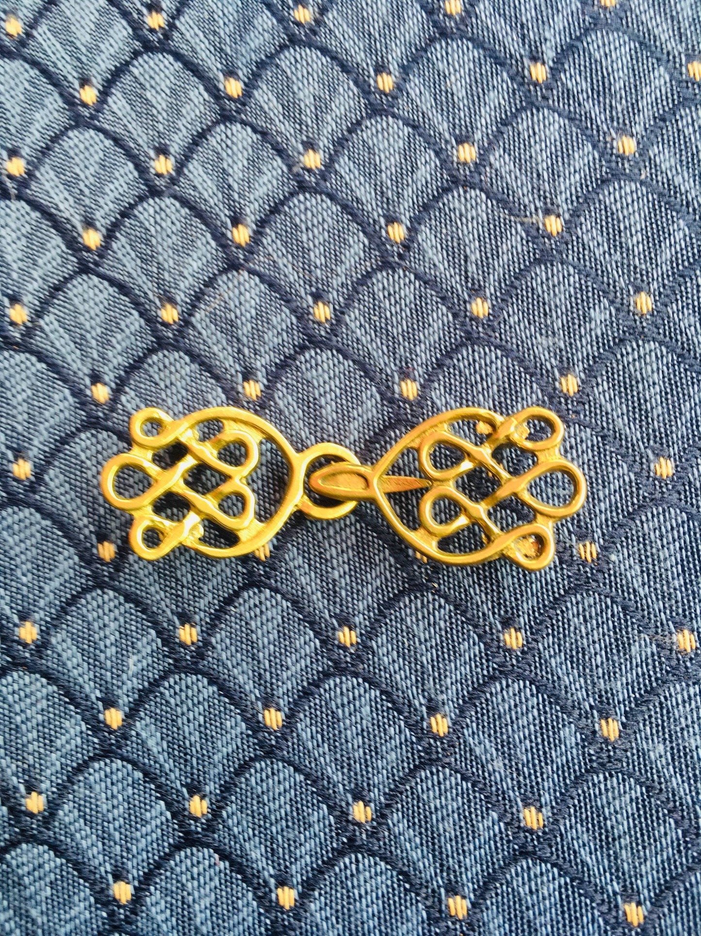 Viking Cloak Clasps - Brass Clasps with interlaced loop pattern displayed on textured blue fabric, perfect for LARP or historical costumes.