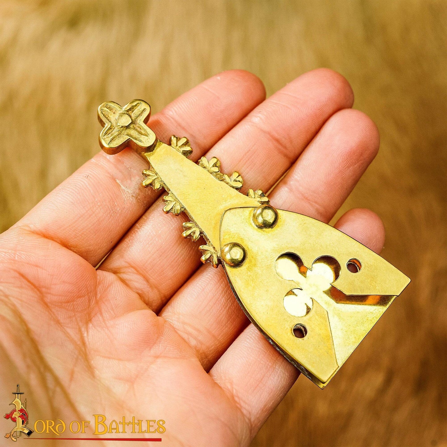 Hand holding a brass medieval strap end with trefoil design, showcasing its size and craftsmanship. A perfect addition to historical and LARP belts.